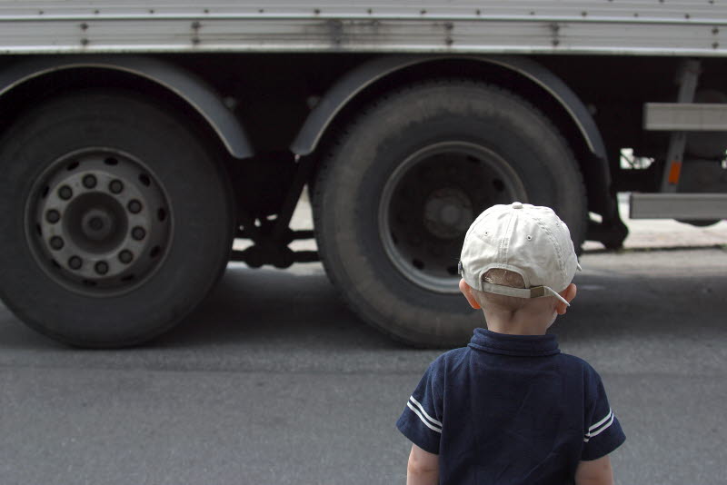 Luftföroreningar. Barn som står och tittar på en lastbil i höjd med hjulen.