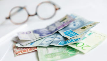 Pengar och glasögon på ett bord 