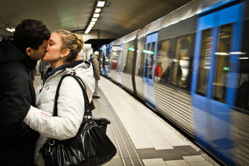 en ung man och kvinna kysser varandra på en tunnelbaneperrong i Stockholm