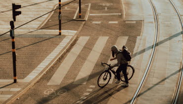 Bild på cyklist i gassande sol på varm gata i innerstaden.