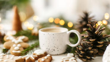 Julbild med pepparkaka, kaffekopp, granris och kottar