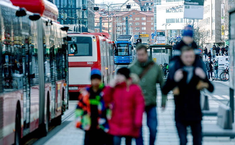 Människor på trottoar i trafikerad stadsmiljö