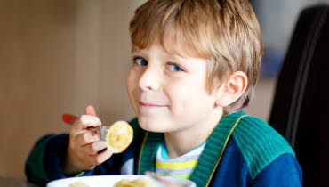 Barn äter pasta i skolmatsal