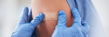 en person får plåster på armen av sjukvårdspersonal efter att ha fått en spruta