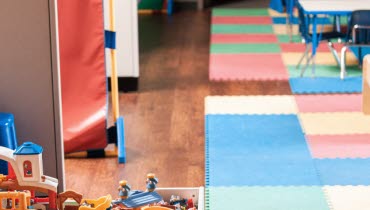 Förksolemiljö alternativt klassrum för yngre barn, med färglada mattor, leksaker och bord och stolar.
