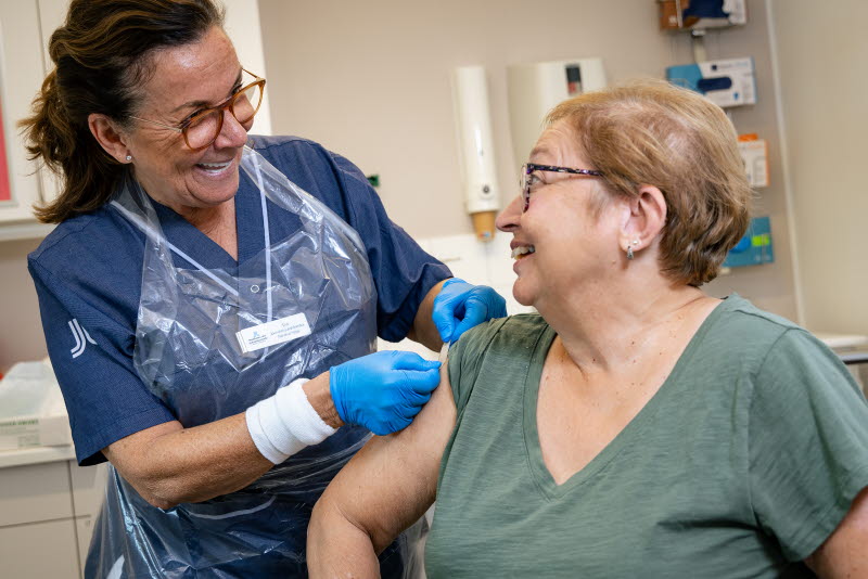 En sjuksköterska sätter på ett plåster på en patients överarm. Foto: Yanan Li
