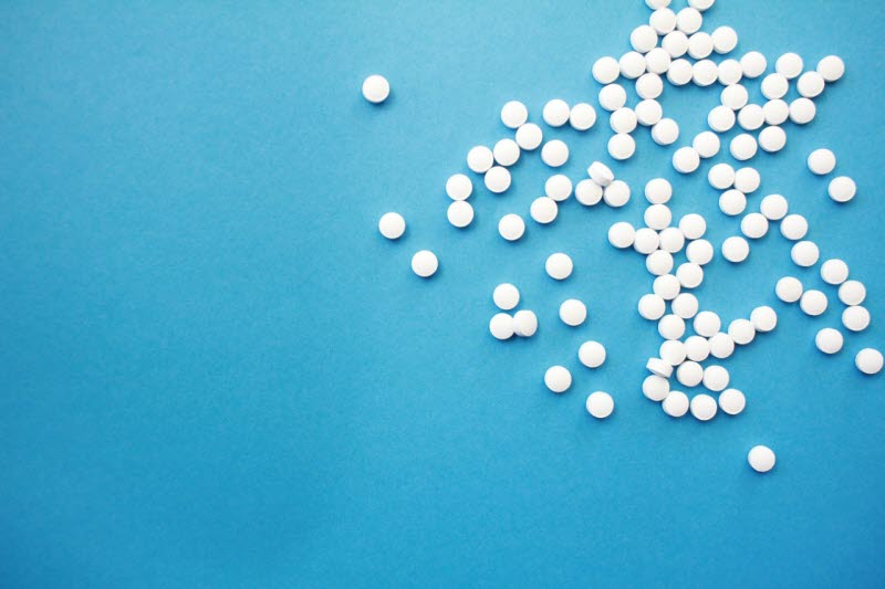 Vita piller ligger utspridda på en blå bakgrund