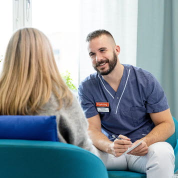 En leende psykolog sitter och pratar med en patient i ett ljust rum. Foto: Yanan Li