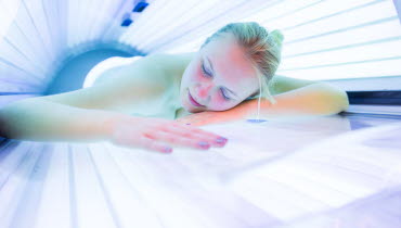 Ung kvinna som ligger i starkt ljus i ett solarium och sover.