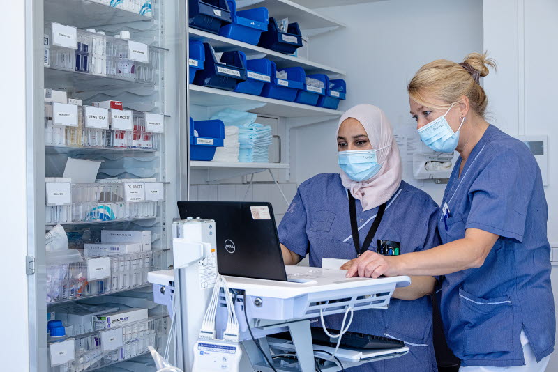 Två vårdmedarbetare står i ett läkemedelsrum och tittar på en datorskärm. Foto: Yanan Li