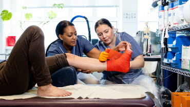En sjuksköterska och en undersköterska gipsar foten på en patient. Foto: Yanan Li