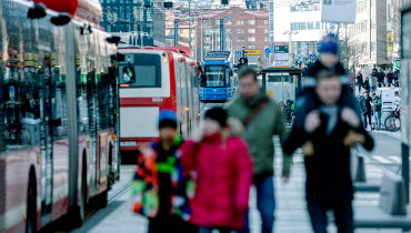Människor på trottoar i trafikerad stadsmiljö