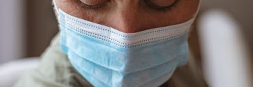 En person i munskydd visar upp sin arm med ett plåster på efter vaccintion. 