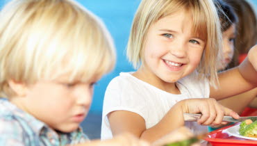 Barn som sitter och äter i matsal