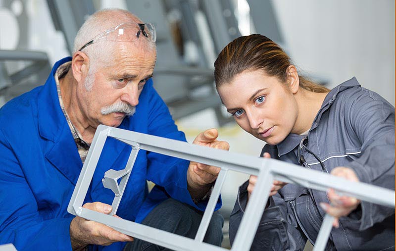 Äldre man och ung kvinna jobbar på byggarbetsplats.