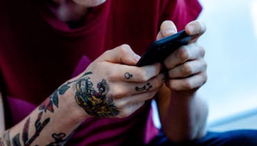 Ung person sitter med mobiltelefon i handen