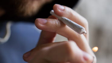 Händer som tänder en cigarett med cannabis
