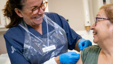 En sjuksköterska sätter på ett plåster på en patients överarm. Foto: Yanan Li