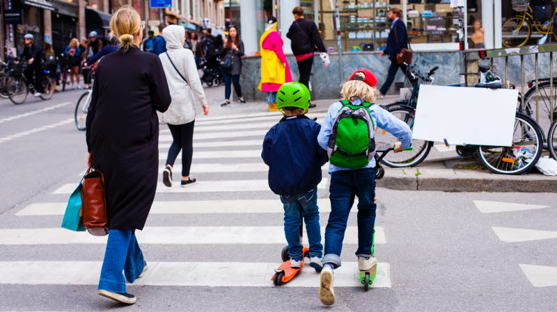 Barn på sparkcyklar vid övergångsställe