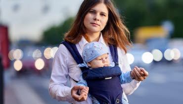 mamma med barn i bärsele i trafikmiljö