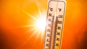 termometer med sol i bakgrunden