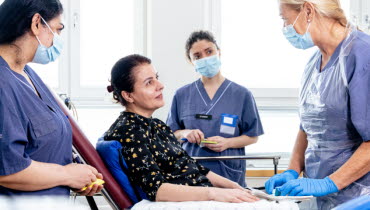 En sjuksköterska på en närakut gör rent ett sår på en patients arm medan två studenter tittar på. Foto: Yanan Li