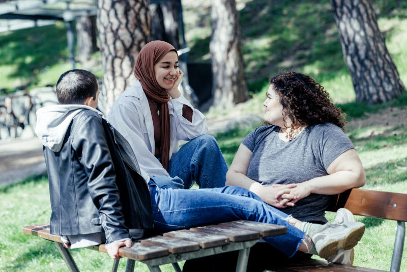 Tre ungdomar diskuterar utomhus