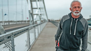 Manlig joggare står och stretchar på en bro. Foto: AdobeStock