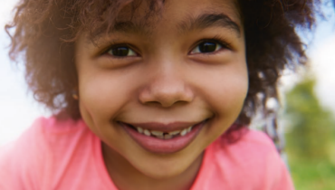 Förstasidan av Folkhälsopolicyn med närbild på leende barn på gunga utomhus 