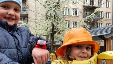 Två förskolebarn visar accelerometrarna de har på handlederna
