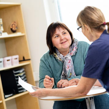 En patient och en vårdpersonal sitter vid ett bord och samtalar kring ett papper. Foto: Yanan Li