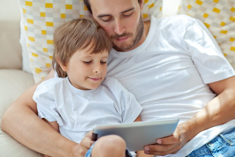 Pappa och barn läser på en ipad