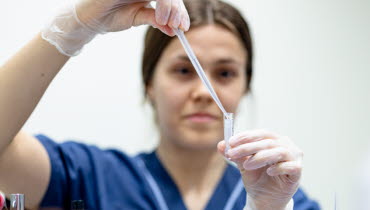 En forskningssjuksköterska droppar med hjälp av en pipett klar vätska i ett provrör. Foto: Yanan Li