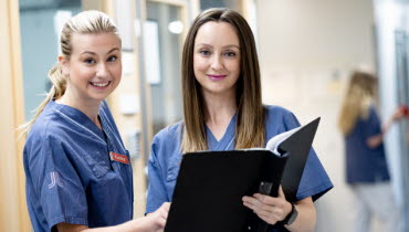 Två sjuksköterskor i sjukhuskorridor