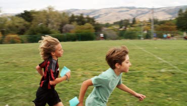 Två barn som springer på en gräsplan