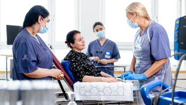 En sjuksköterska på en närakut gör rent ett sår på en patients arm medan två studenter tittar på. Foto: Yanan Li