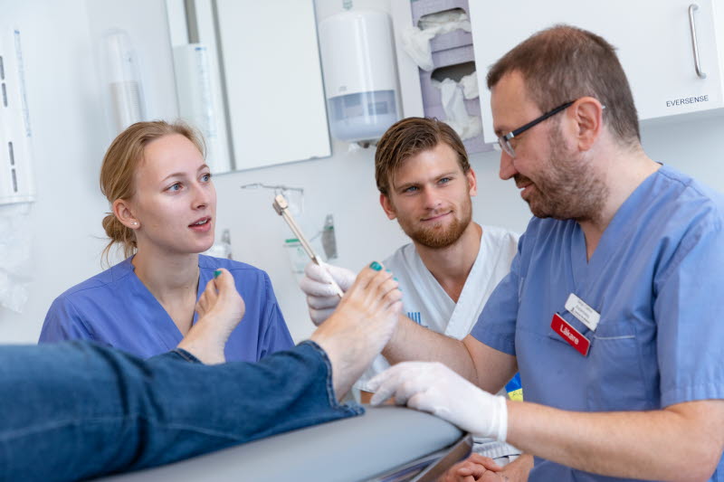 En läkare visar undersökning av fötter för två studenter. Foto: Yanan Li