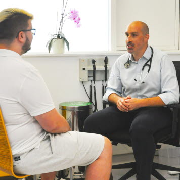 En patient och en vårdgivare sitter i ett undersökningsrum och pratar. Foto: ECPO Media